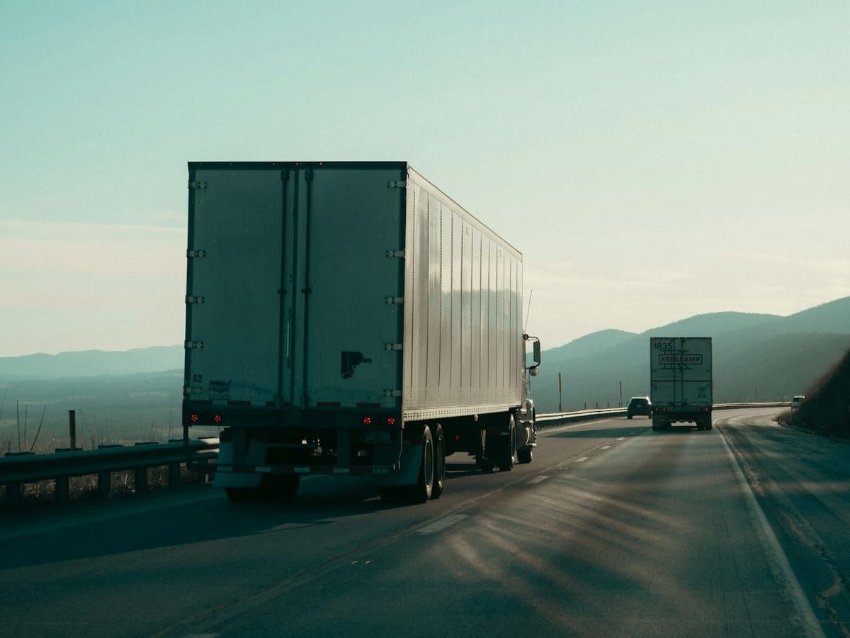Two trucks with trailers on a highway in the hills