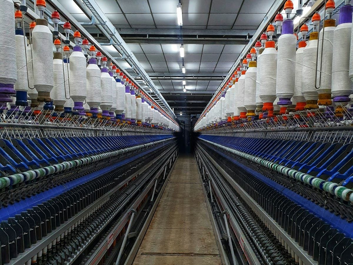 Rows of spinning frames with white yarn in a textile mill
